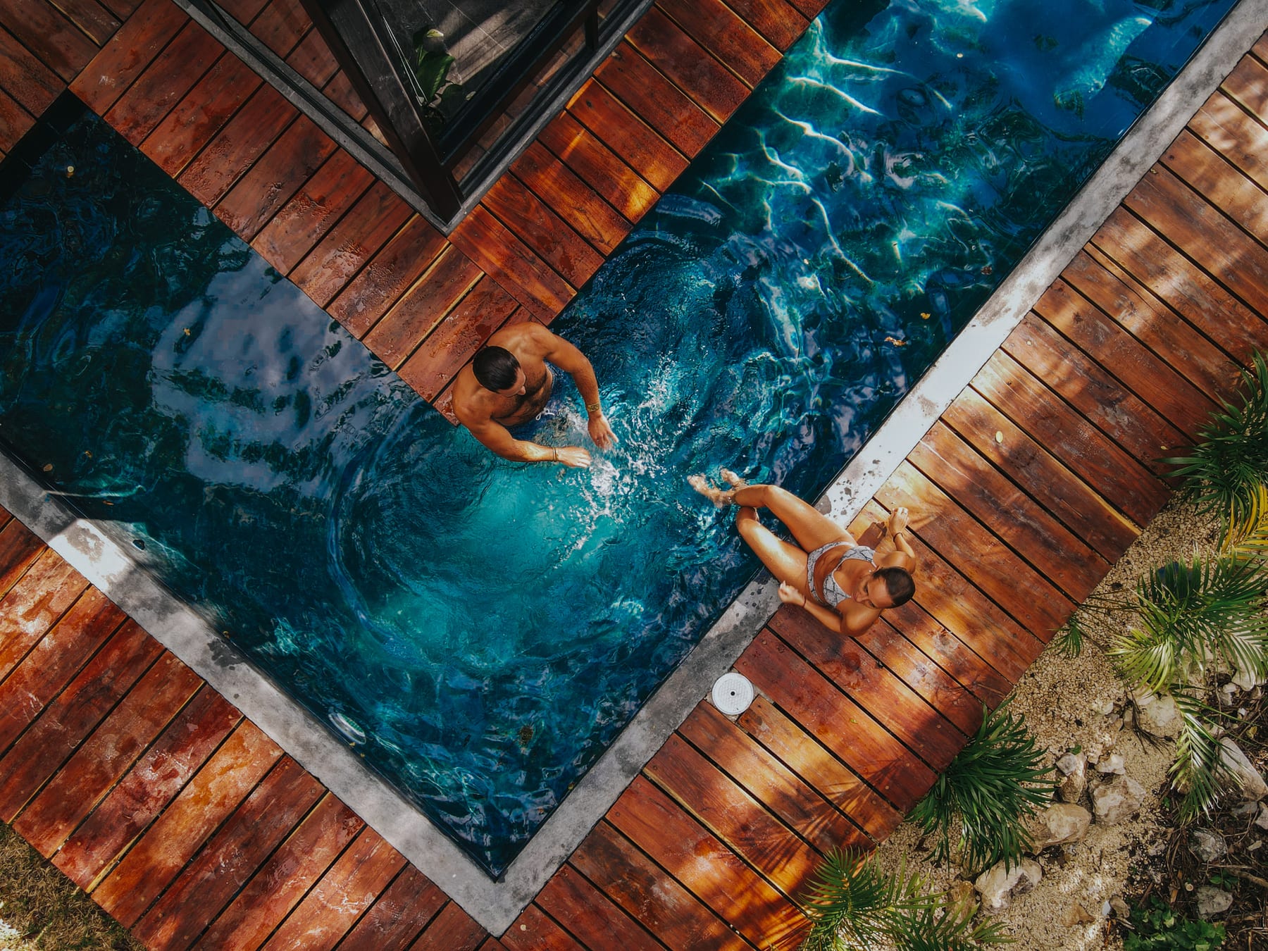 Piscine bordée d’une terrasse en bois, baigneurs vus du ciel